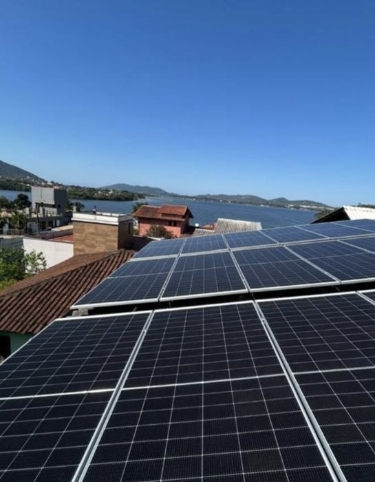 Painéis solares em telhado residencial com vista para a lagoa e os morros
